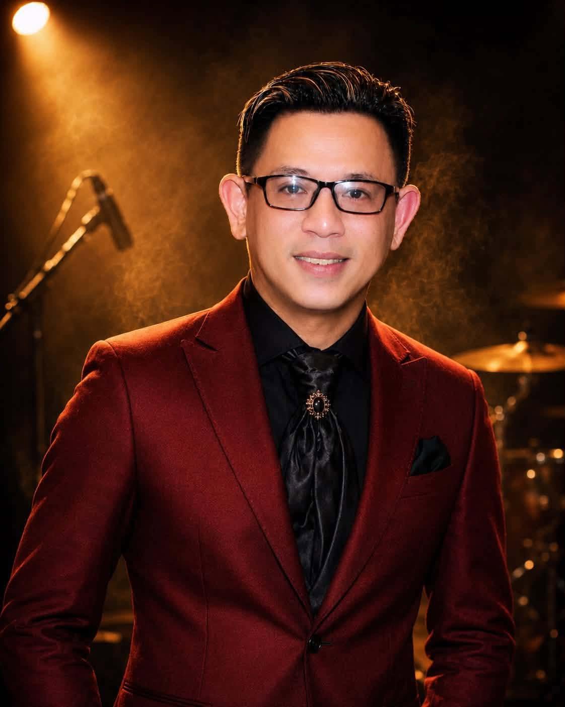 Artist Thong Nguyen wearing glasses and a burgundy velvet suit